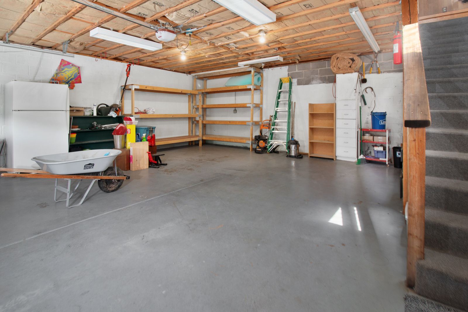 A clean garage with a swept floor and belongings organized on shelves along the walls